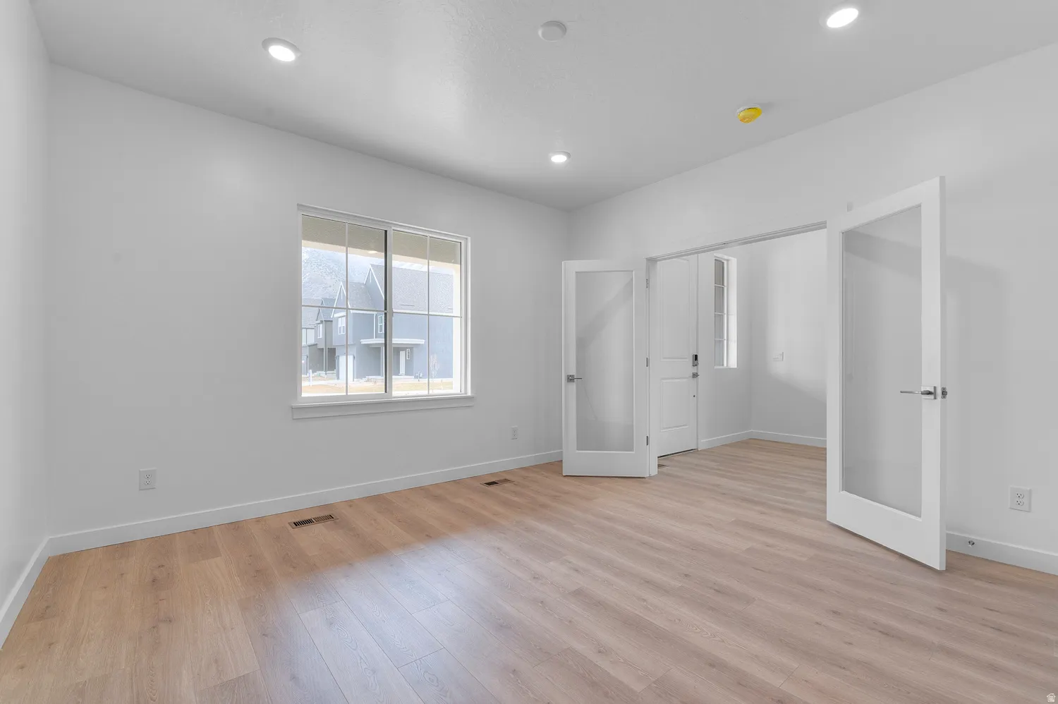Recessed lighting, wood-finish flooring, white walls, and French doors with frosted glass panels