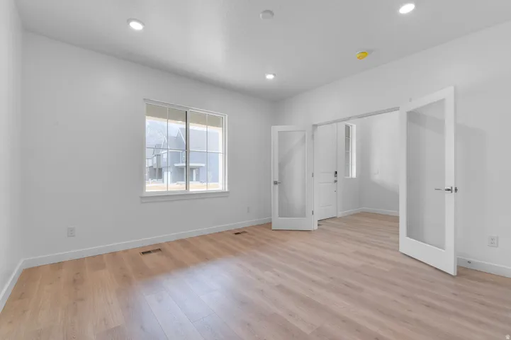 Recessed lighting, wood-finish flooring, white walls, and French doors with frosted glass panels