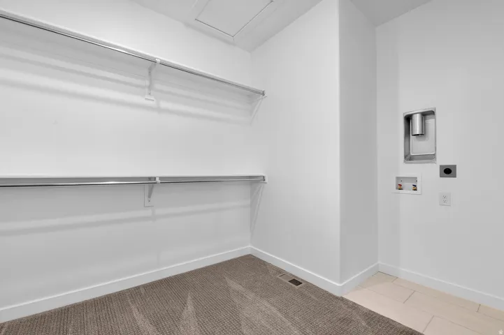 Bright, minimalist storage room featuring dual wall-mounted aluminum shelving units, neutral wall finishes, and mixed flooring with carpet and tile sections