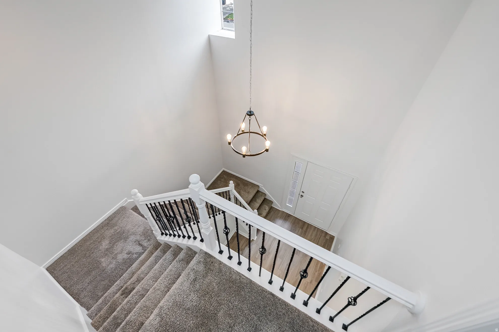 Two-story foyer with a decorative chandelier, white walls, and a window for natural light