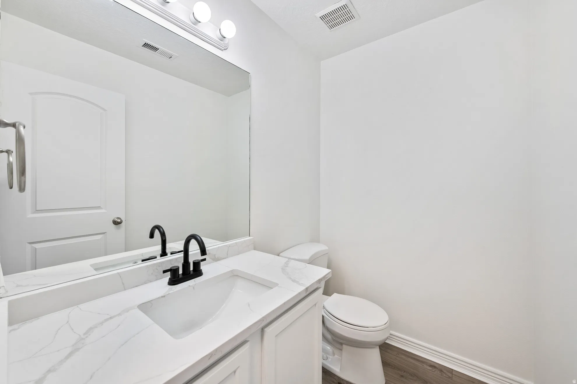 White vanity with an integrated rectangular sink, matte black faucet, and a patterned countertop
