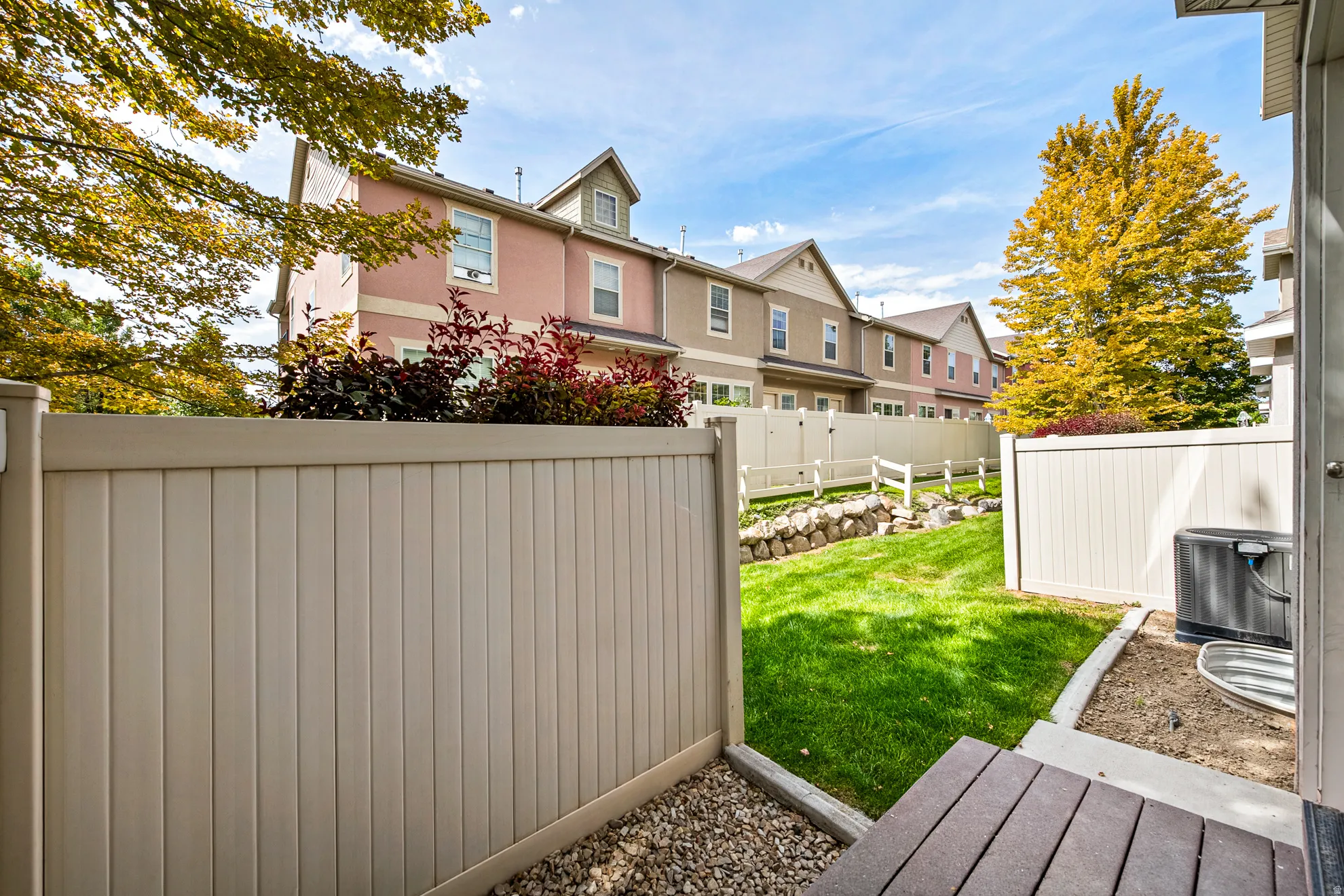 Enclosed backyard featuring a composite deck, gravel border, and manicured lawn