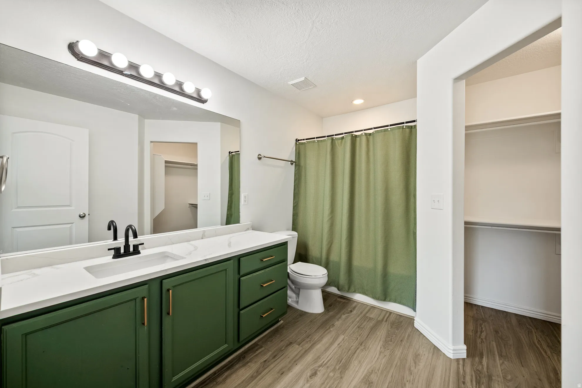 Vanity with green cabinetry, white countertop, and black fixtures
