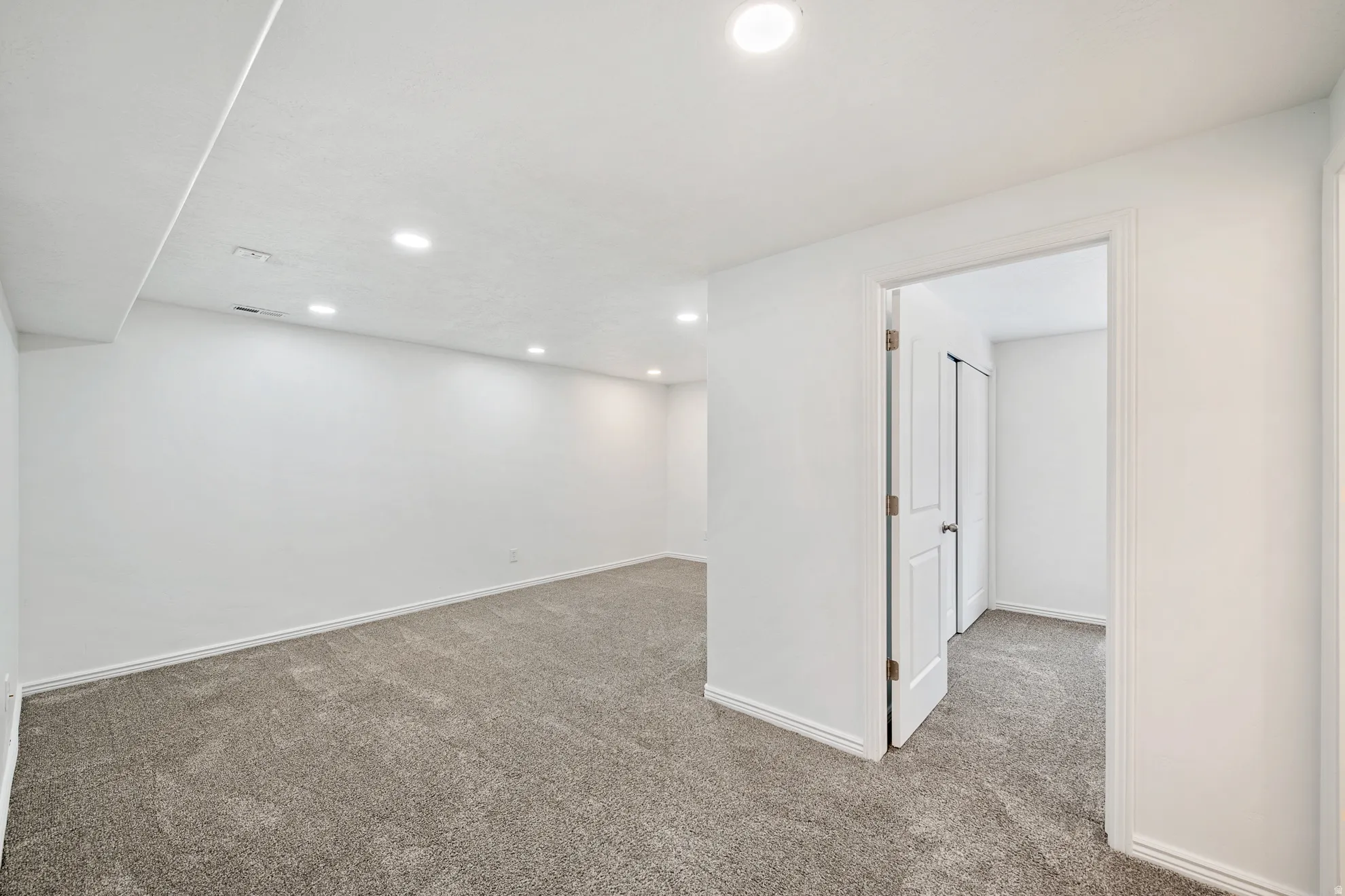 Recessed lighting, light gray carpeting, white walls, and white trim