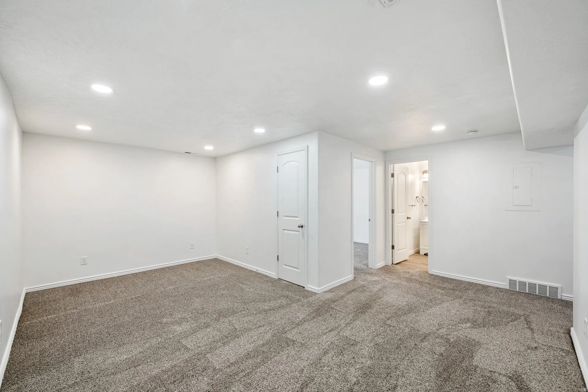 Recessed lighting, plush carpeting, and white painted walls