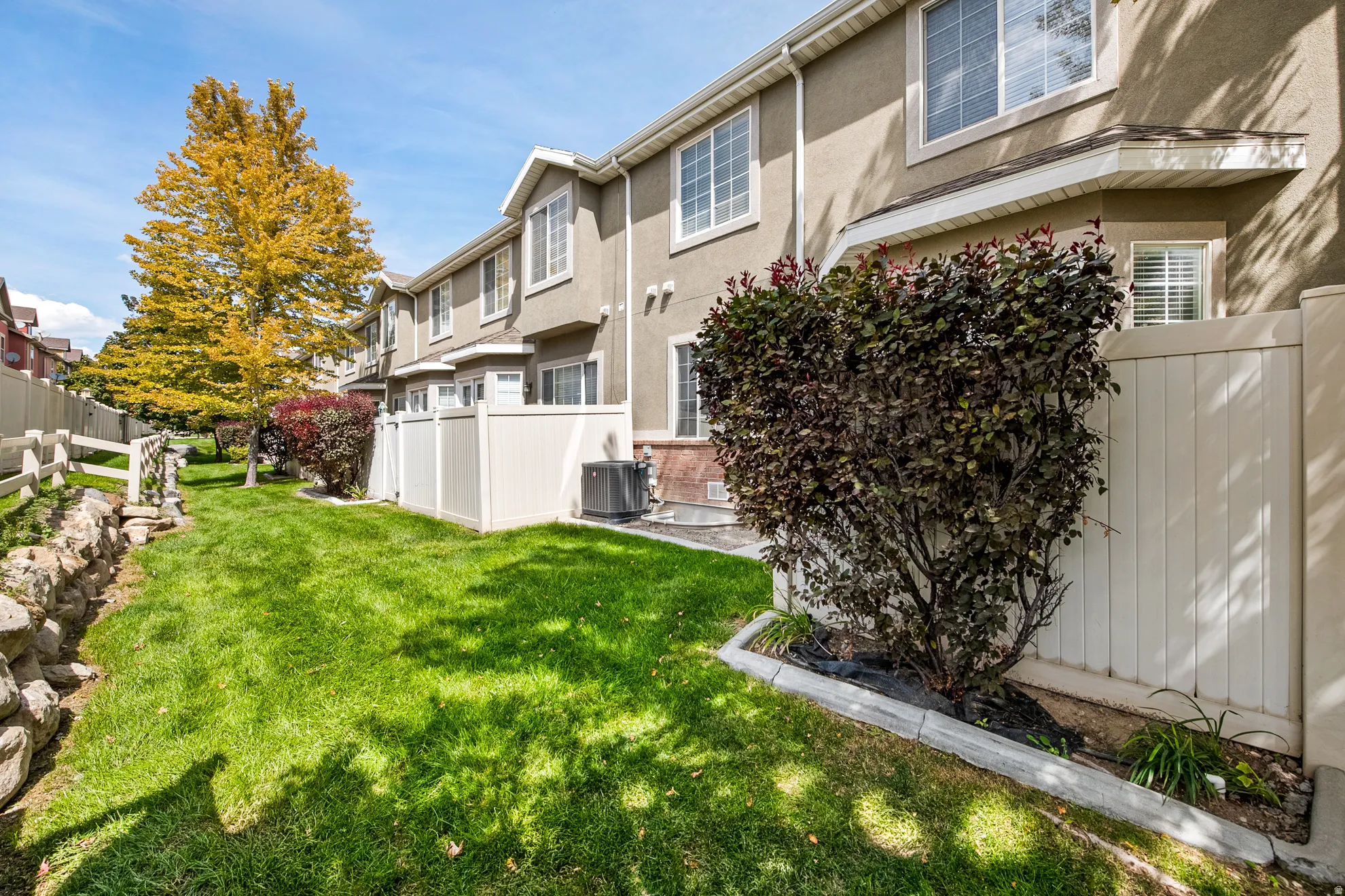 Expansive green lawn, privacy fencing, established landscaping, and stucco exterior