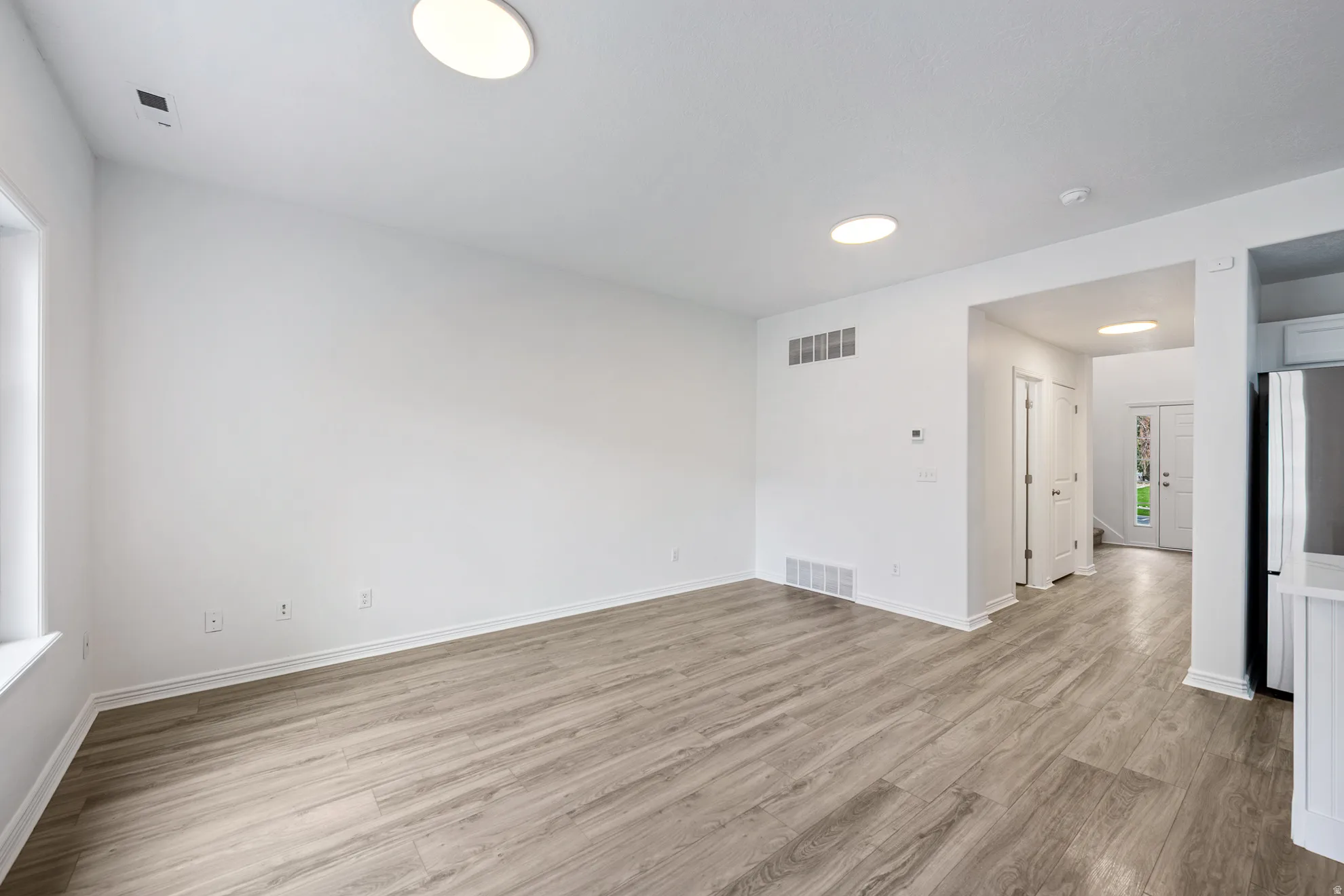 Recessed lighting illuminating wood-finish flooring, white walls, and white trim