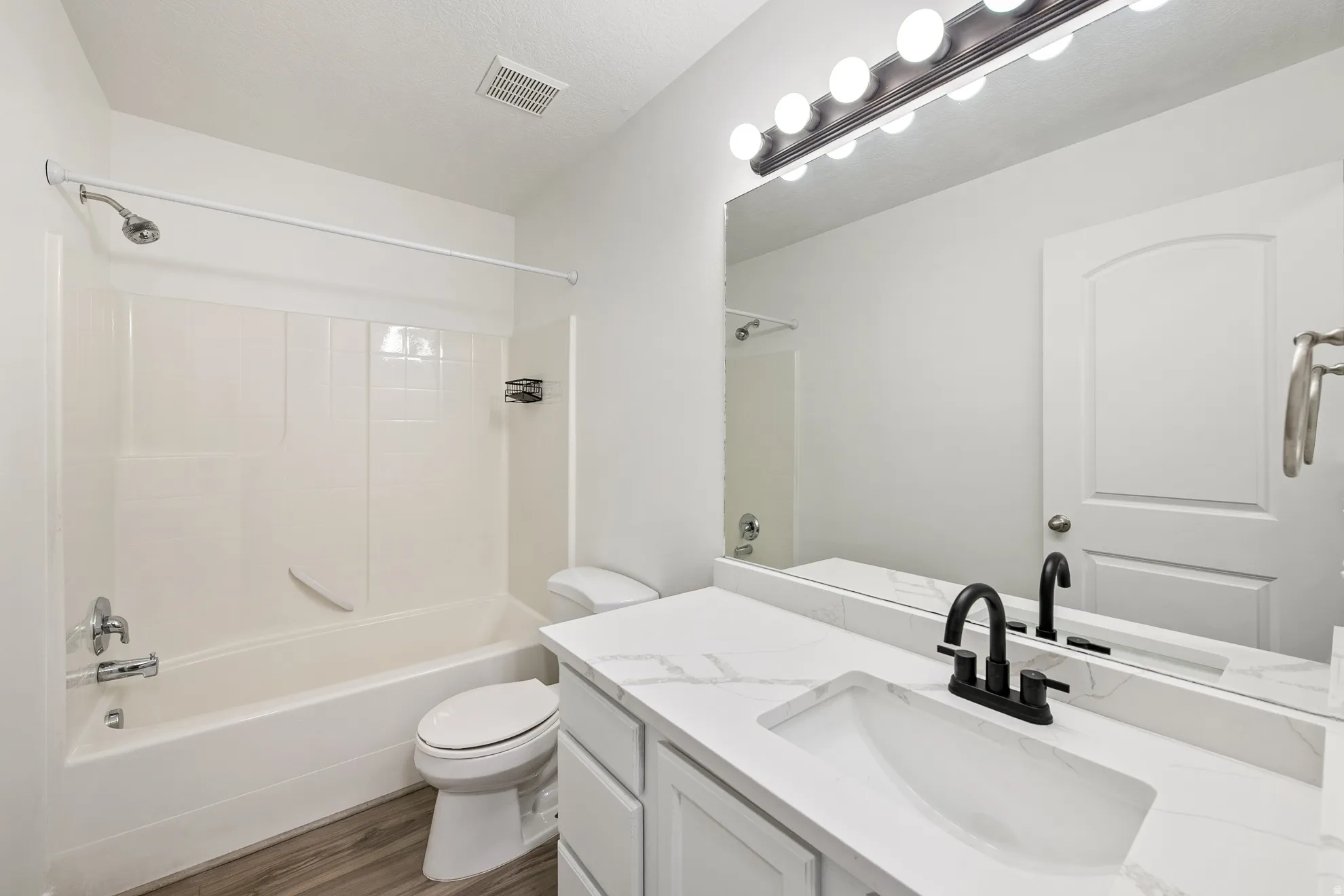 White vanity with a stone-finish countertop, undermount sink, and black-finish faucet