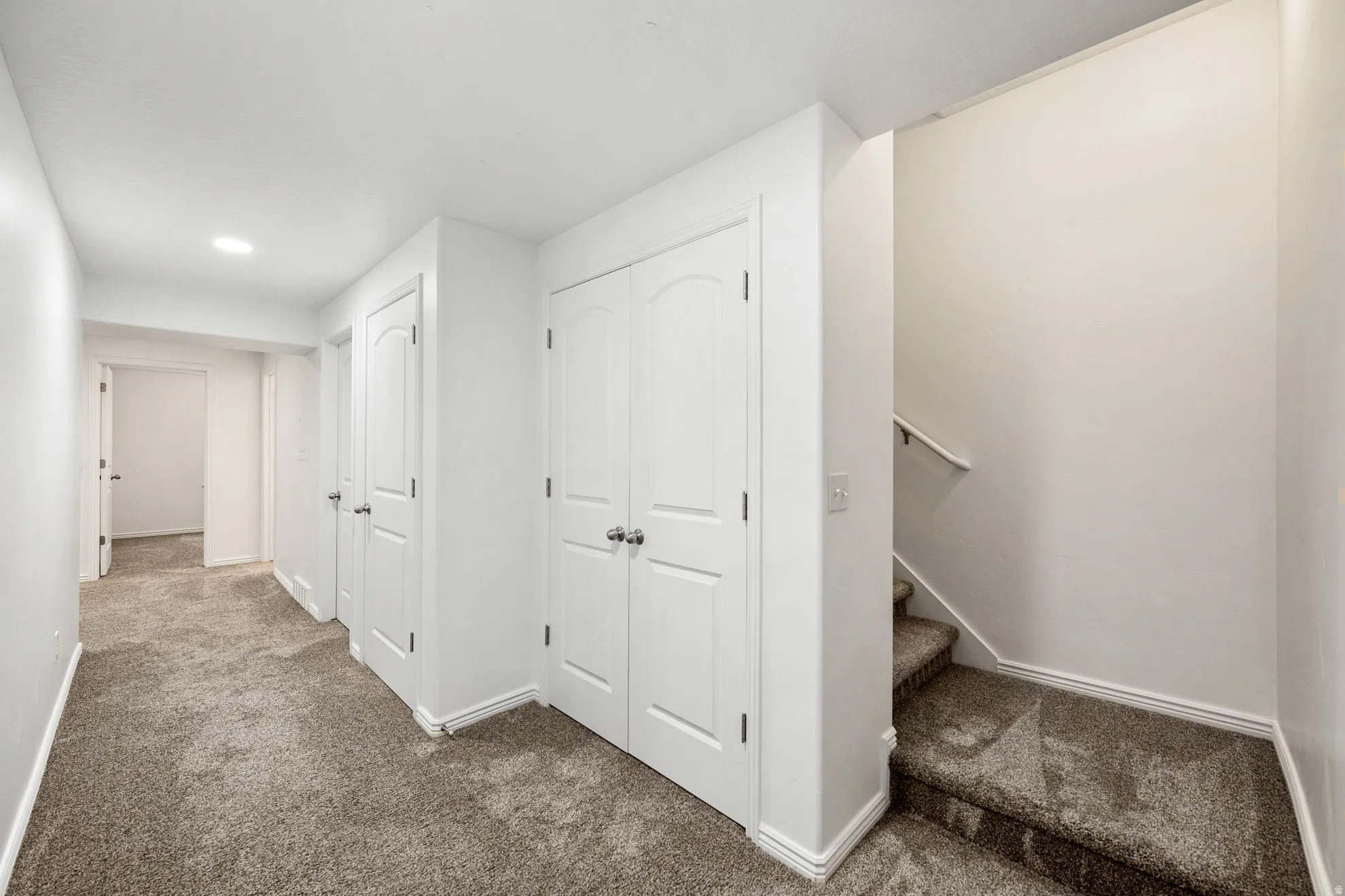 Hallway featuring multiple paneled doors, recessed lighting, and carpeted flooring