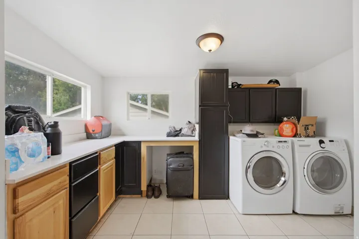 White flat-panel ceiling, ceiling-mounted light fixture, multiple windows, L-shaped countertop, and built-in cabinetry