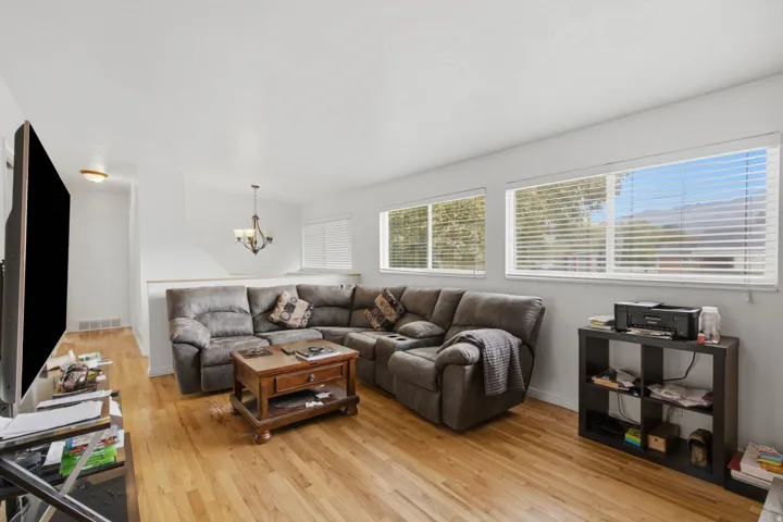 Hardwood-finish flooring, multiple windows with blinds, recessed lighting, and a decorative chandelier