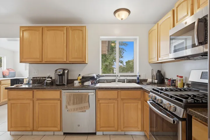 Light wood-finish cabinetry with stainless steel appliances, a built-in microwave, and a gas range