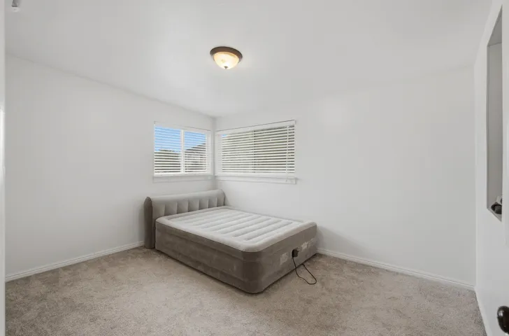 Bright room featuring two windows with horizontal blinds, neutral wall paint, and carpet flooring
