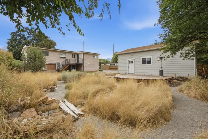Expansive backyard featuring a gravel pathway, raised wood deck, and a detached structure with a side entrance