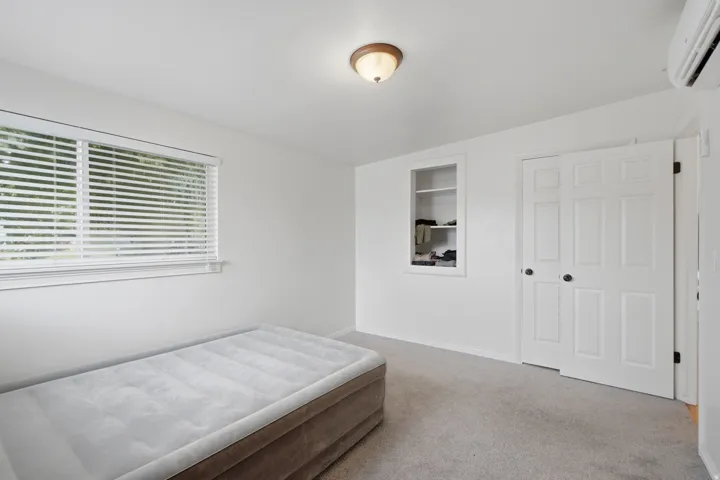 Carpeted flooring, white walls, and a built-in shelving unit