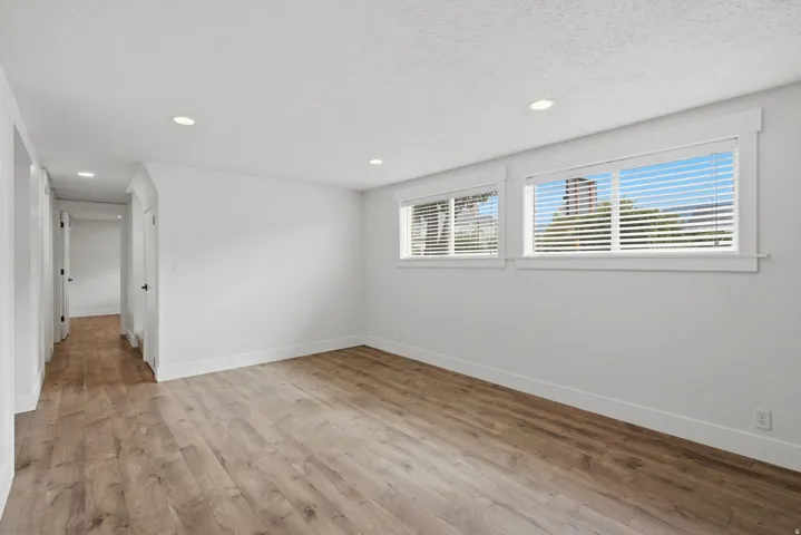 Recessed lighting, wood-finish flooring, white walls, multiple windows with blinds, and white trim
