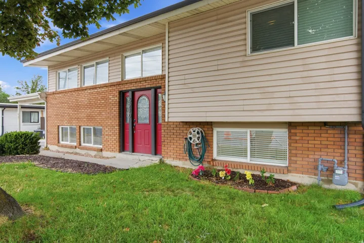 Brick and siding exterior with a red door entry