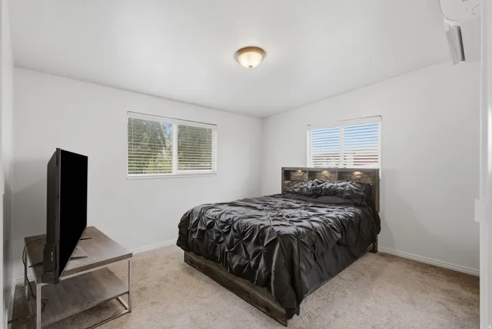 Carpeted room with white walls, two windows featuring blinds, and a flush mount ceiling light fixture