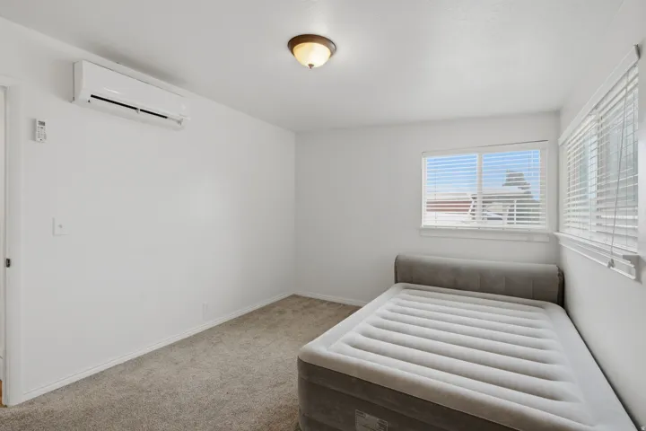 Split-system air conditioning unit, flush-mount ceiling light, and window with horizontal blinds