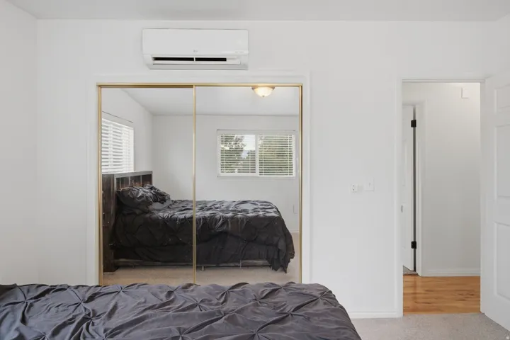 Mirrored closet doors, wall-mounted climate control unit, and white interior doors