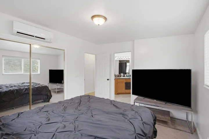 White walls throughout, mirrored closet doors, and wood-finish flooring