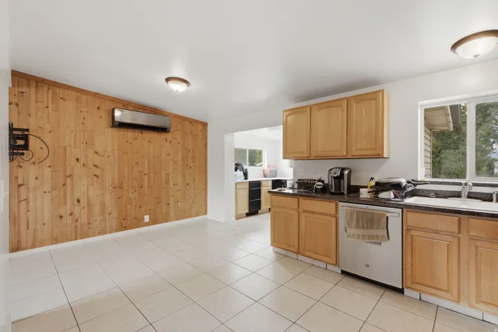 Kitchen with natural wood cabinetry, dark countertops, and tile flooring