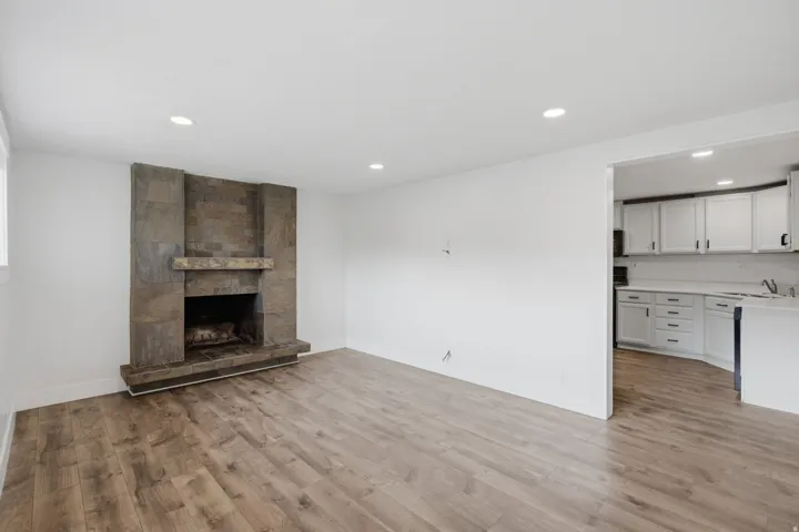 Wood-finish flooring, recessed lighting, and a stone-clad fireplace