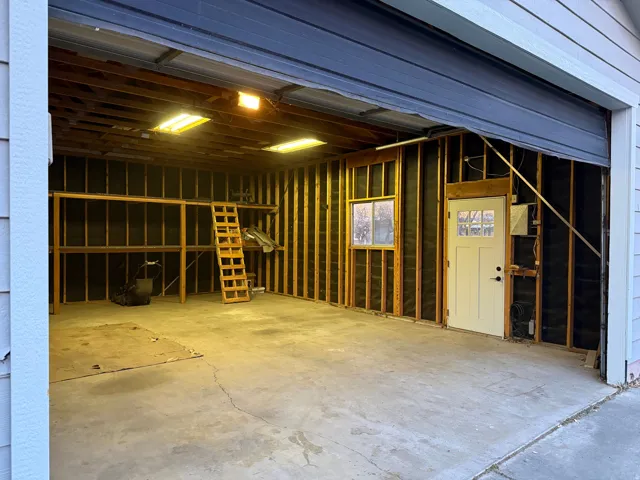 Spacious garage with exposed framing, concrete flooring, and built-in shelving