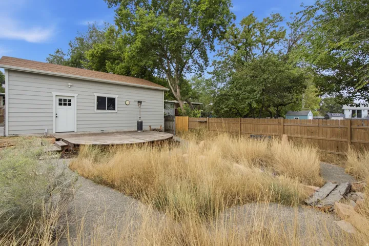 Siding exterior with a built-in deck, secure perimeter fencing, and mature trees