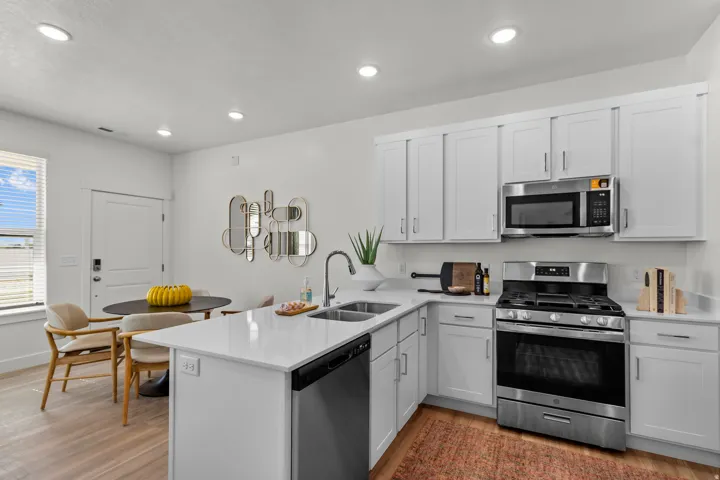 Kitchen featuring white cabinetry, stainless steel appliances, white countertops, and wood-finish flooring