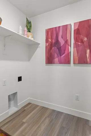 Wood-finish flooring with white baseboards, white walls, and a white wall-mounted shelf