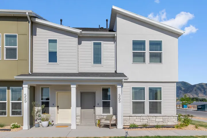 Modern townhome featuring a covered entry, horizontal siding, stone facade, and a sloped roofline