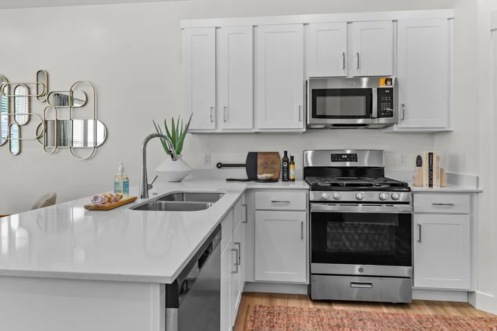 Kitchen featuring white shaker cabinetry, stainless steel appliances, a double basin sink, and light countertops