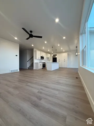 Kitchen area featuring white cabinetry, a center island, wood-finish flooring, recessed lighting, and large windows