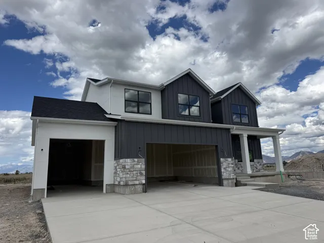 Contemporary exterior design with board and batten siding, stone accents, black-framed windows, a covered entry, and an attached two-car garage
