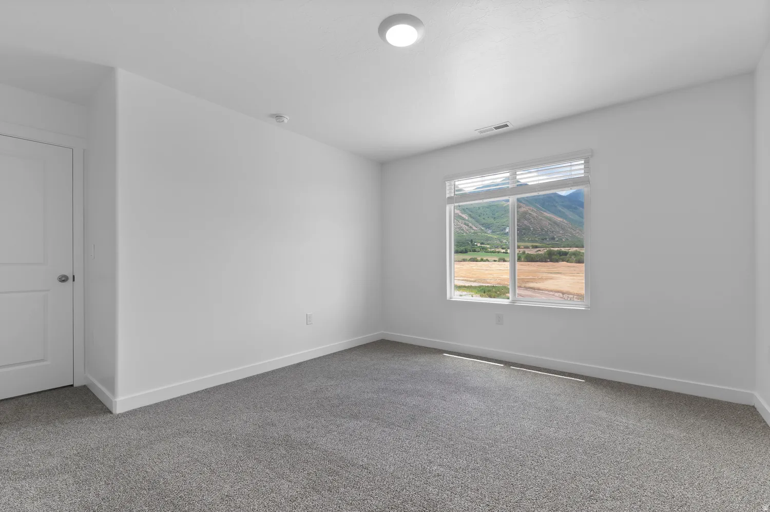 Recessed ceiling lighting, white walls, gray carpet, white trim, and a large window