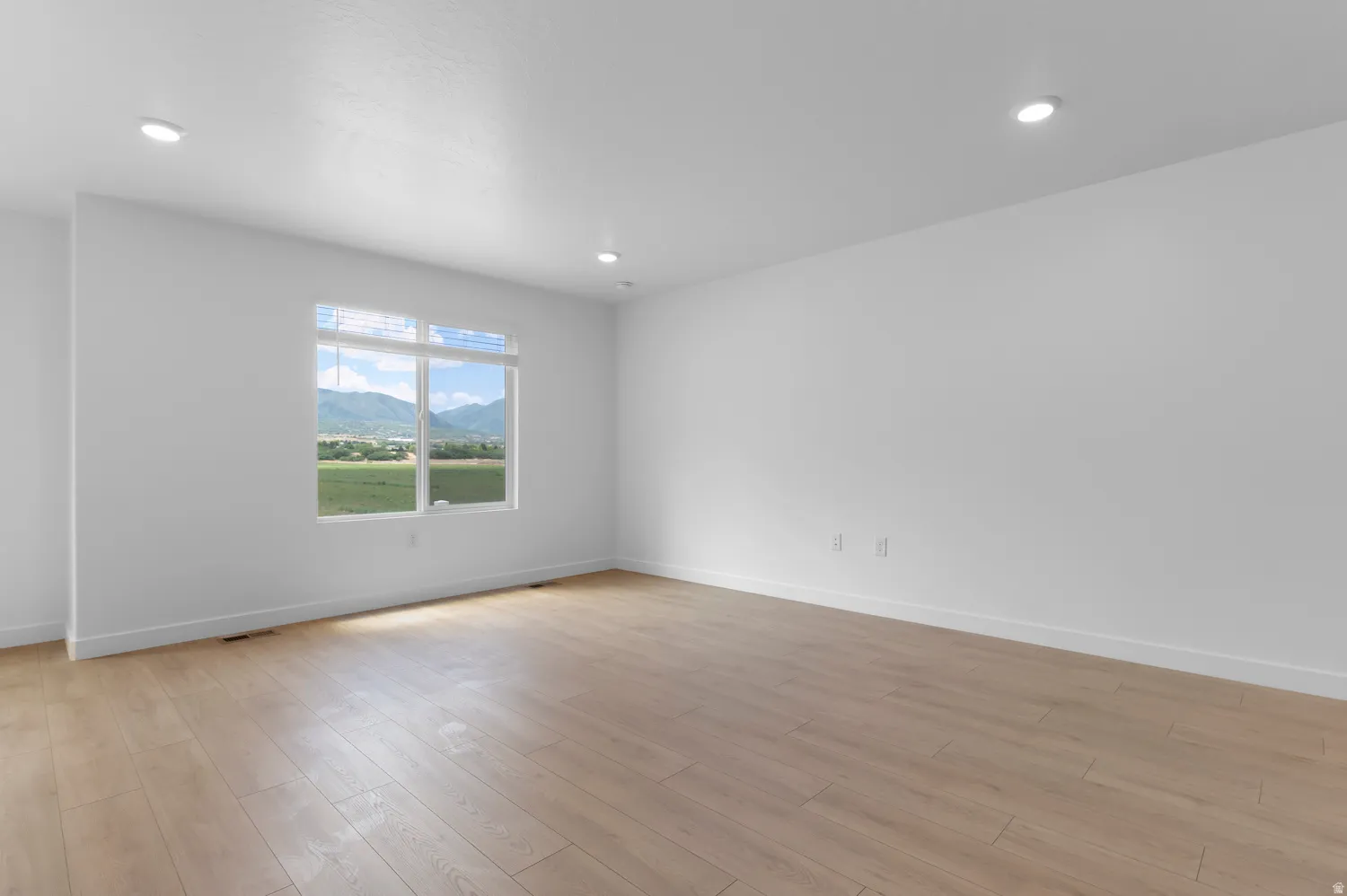 Recessed ceiling lighting, wood-finish flooring, and a window with mountain and field scenery