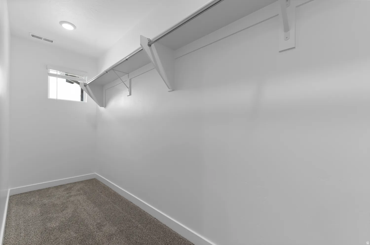 Built-in shelving, carpeted flooring, recessed ceiling lighting, and an exterior window