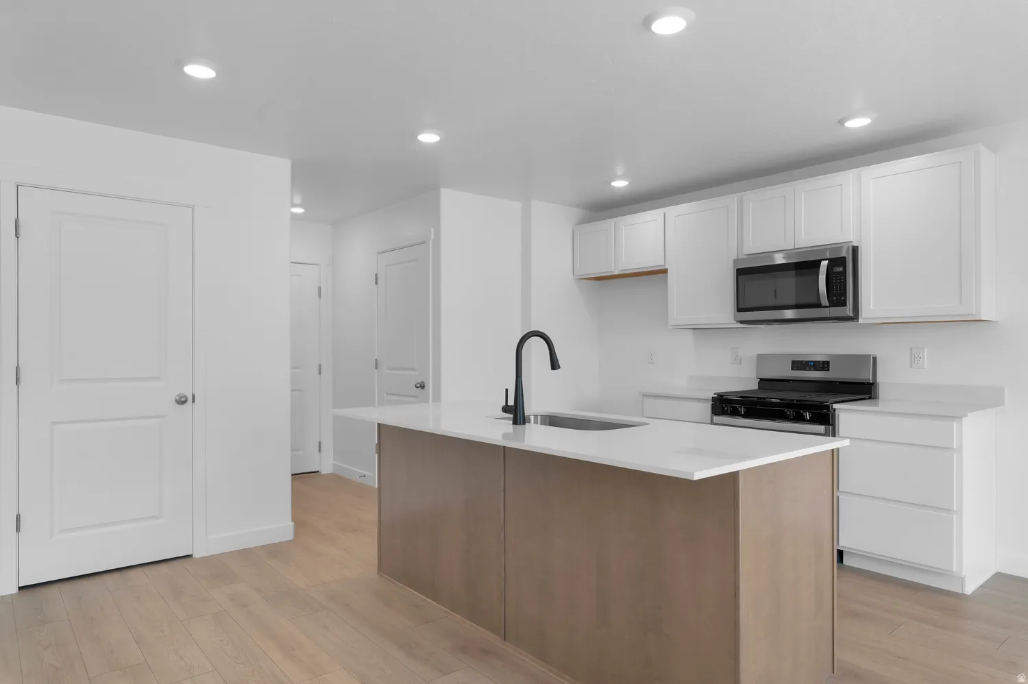 Kitchen featuring a center island, stainless steel appliances, white cabinetry, recessed lighting, and wood-finish flooring