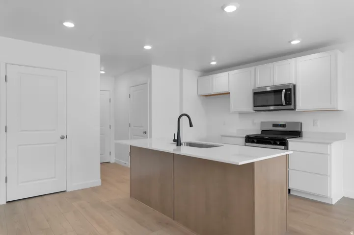 Kitchen featuring a center island, stainless steel appliances, white cabinetry, recessed lighting, and wood-finish flooring