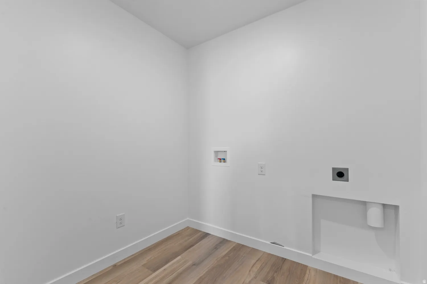 Utility room featuring wood-finish flooring, white walls, washer hookups, and dryer hookups