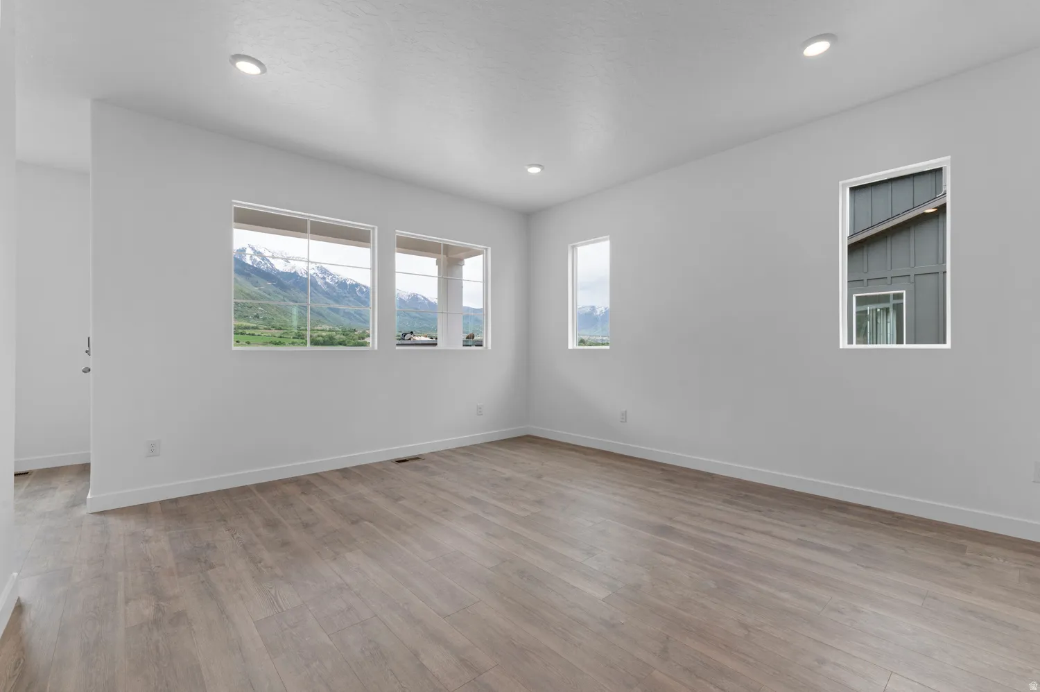 Spacious interior with neutral white walls, wood-finish flooring, and recessed lighting