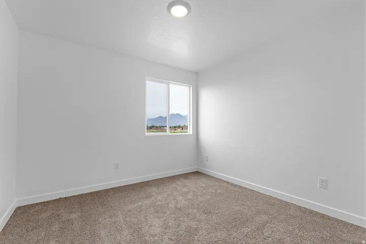 Bright interior with neutral-toned carpet, a single window, and a flush-mount ceiling light