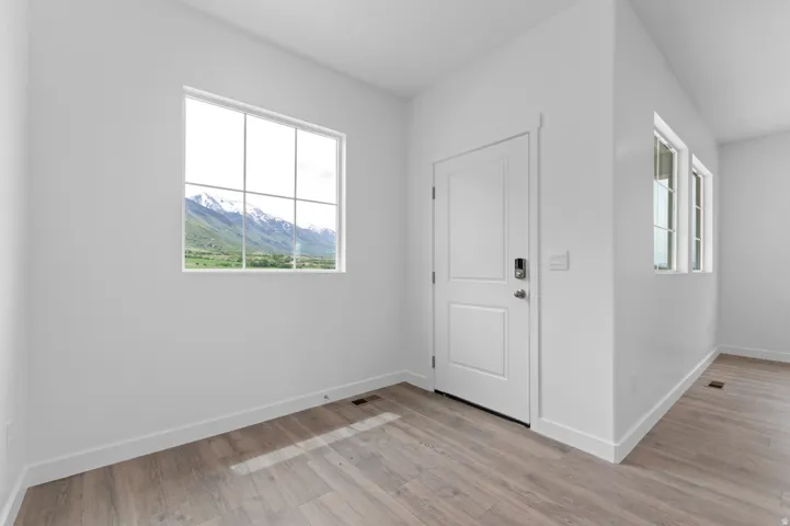 Wood-finish flooring, white walls, white window trim, white paneled door, and mountain scenery