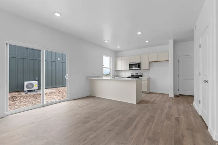 Open-concept living space featuring wood-finish flooring, recessed lighting, and a kitchen island with stone countertops