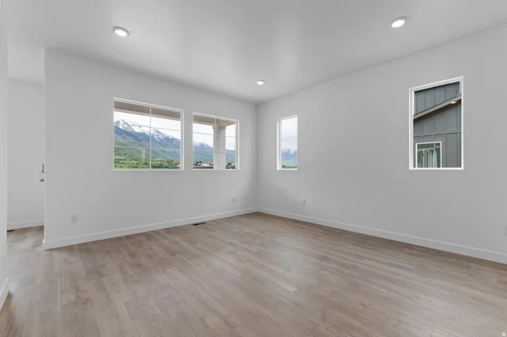 Spacious interior with neutral white walls, wood-finish flooring, and recessed lighting