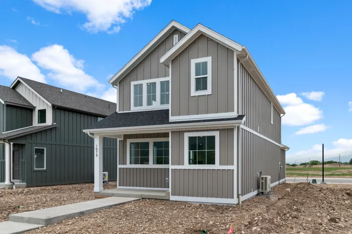 Two-story exterior with board and batten siding, white trim accents, and a covered porch with white columns