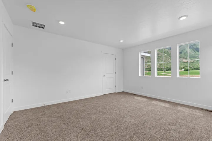 Plush carpeting, recessed lighting, and three large windows