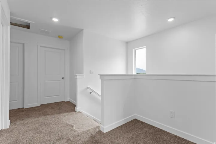 White interior walls, recessed lighting, carpeted flooring, interior doors, and a window