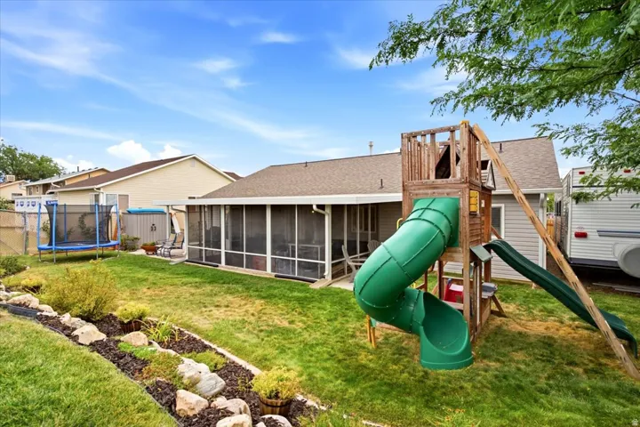 Expansive backyard featuring a screened-in porch, established landscaping, and a fenced perimeter